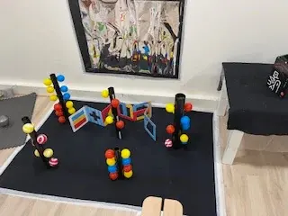 Boules et constructions colorées sur un tapis contrasté.