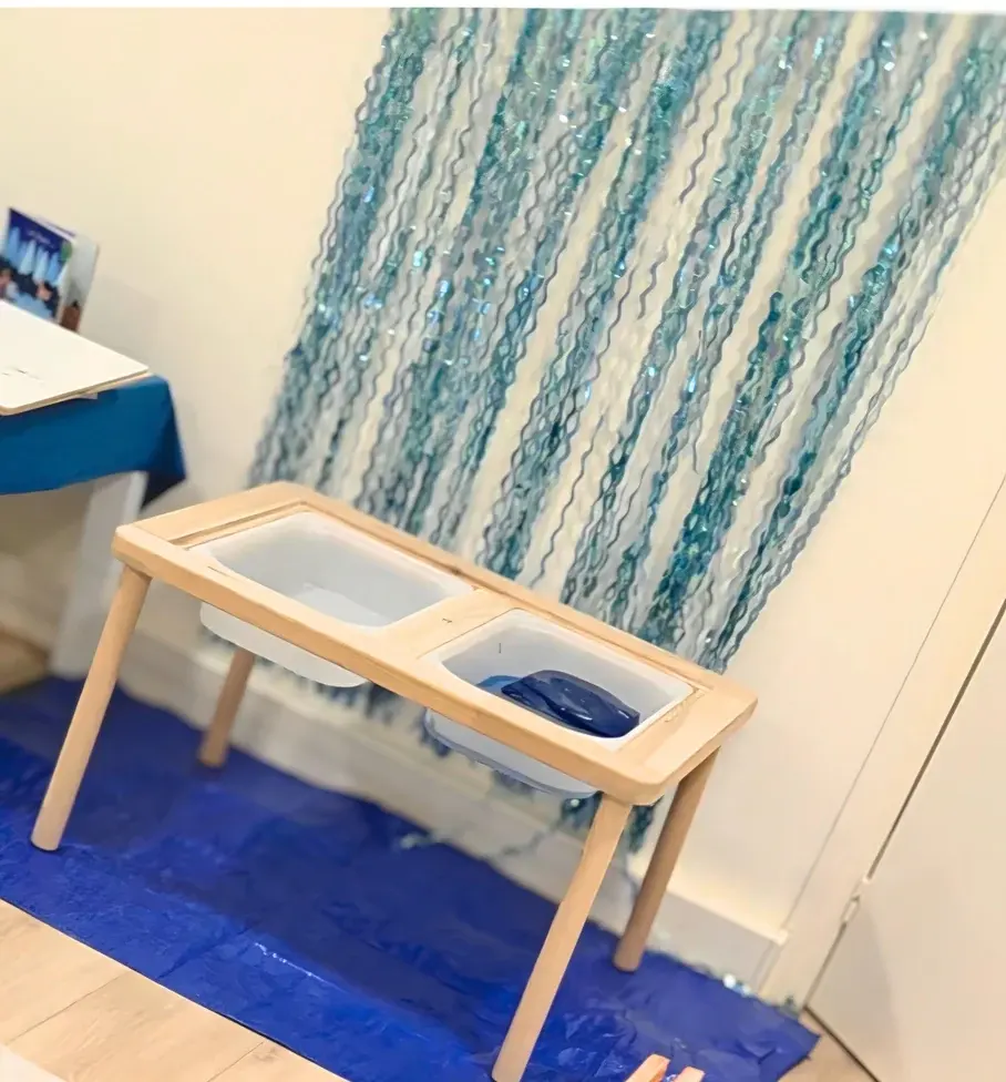 Bacs sensoriels de transvasement devant un rideau de fils bleus chez JEUXSENS.